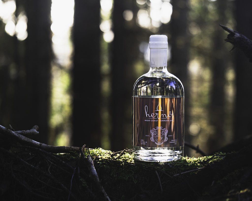 Hernö High Coast Terroir 2020 flaska står på en stock i skogen.