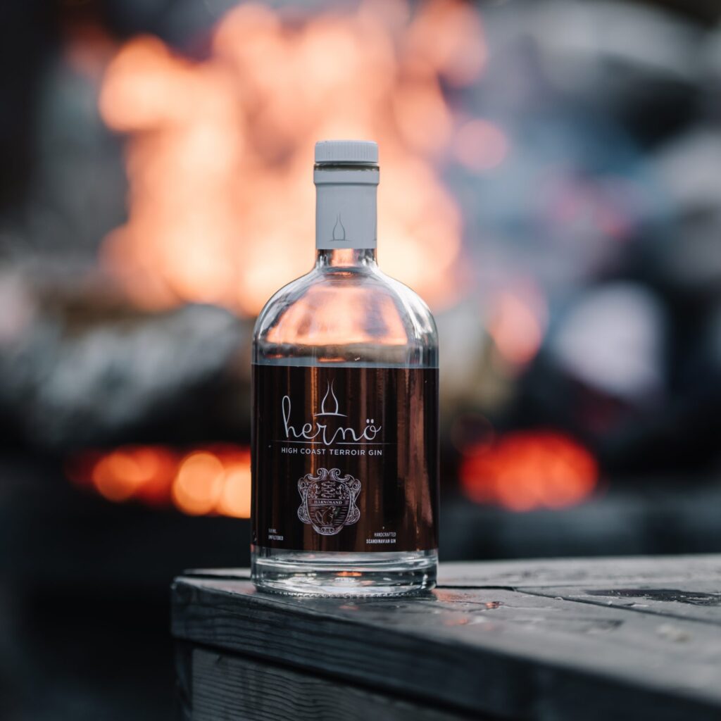 Hernö High Coast Terroir Gin 2019 flaska framför en brasa utomhus.